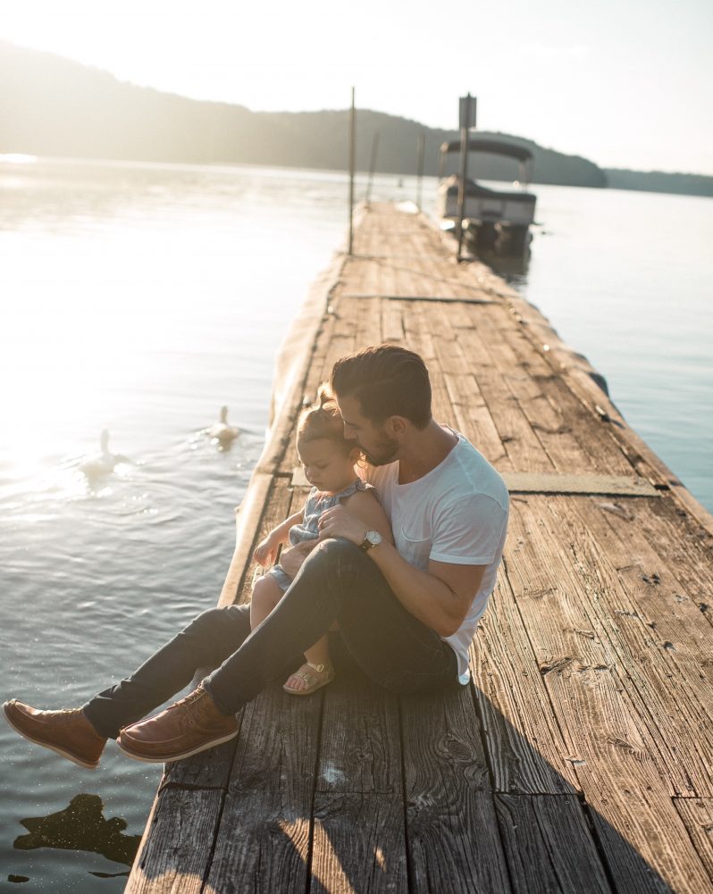 mann with baby sitting on a dock